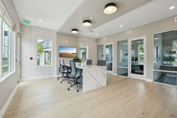 A room with a desk, chairs, and a television.